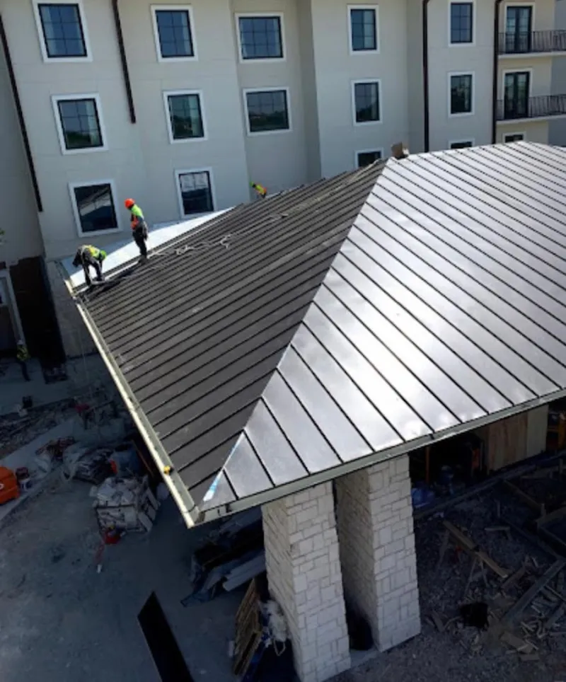 Crew installing standing seam metal roof panels on a commercial project in Thief River Falls